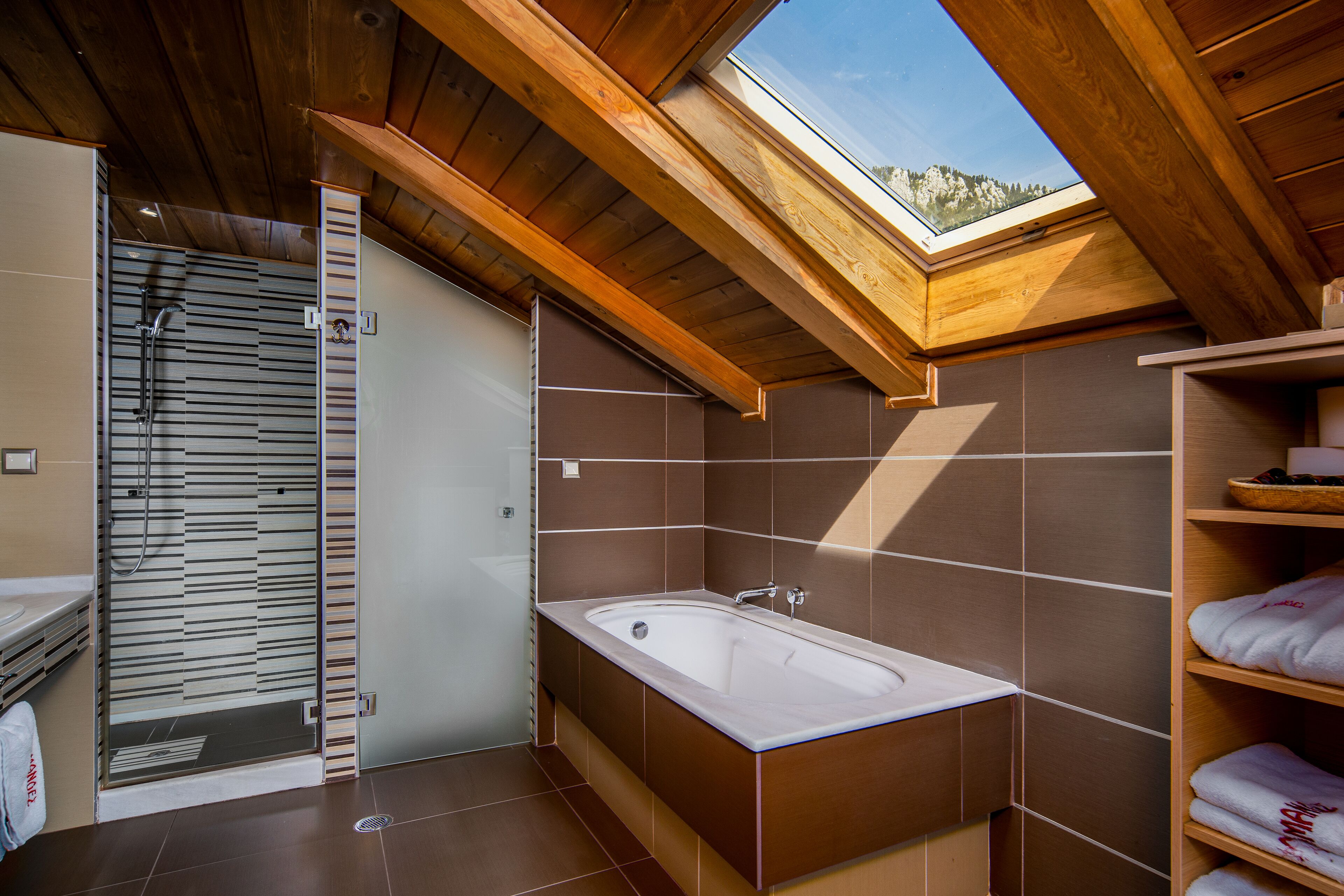 A modern bathroom with a skylight, a bathtub, and a shower enclosure.