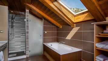 A modern bathroom with a skylight, a bathtub, and a shower enclosure.