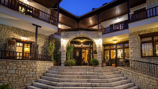 A stone building with a central entrance, multiple balconies, and outdoor seating areas. - Giamandes Hotel (Pyli)