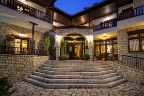 A stone building with a central entrance, multiple balconies, and outdoor seating areas. - Giamandes Hotel (Pyli)
