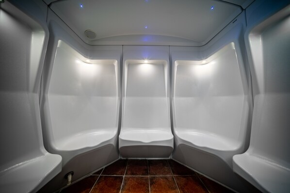 Un baño moderno con tres orinales blancos y suelo de baldosas.