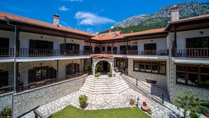 A two-story building with a stone facade, a central courtyard with steps, and balconies on each floor. - Giamandes Hotel (Pyli)