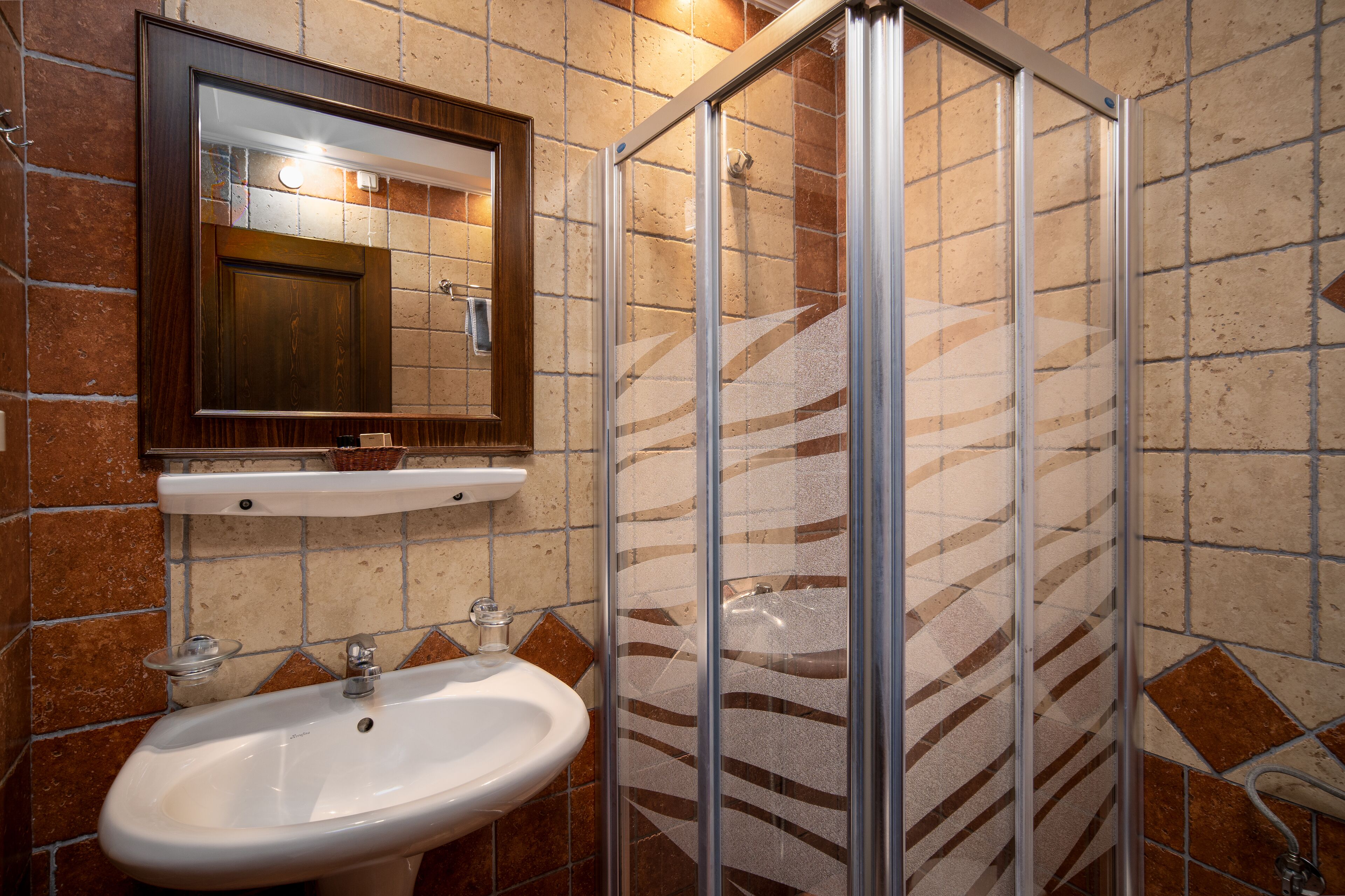 Un baño con lavabo, espejo y cabina de ducha.