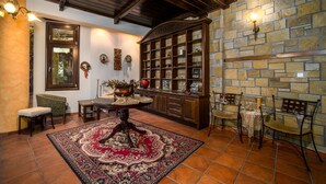 A traditional interior with a stone wall, wooden furniture, and a tiled floor. - Giamandes Hotel (Pyli)