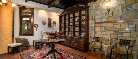 A traditional interior with a stone wall, wooden furniture, and a tiled floor.