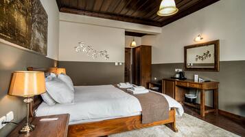 A hotel room with a wooden bed, a nightstand, a desk, and a mirror.