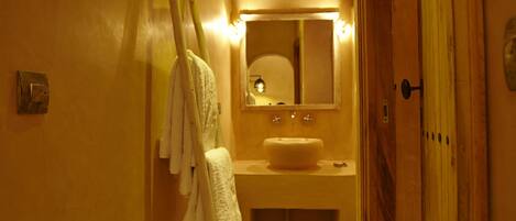A narrow hallway with a wooden door, a mirror, and a sink.