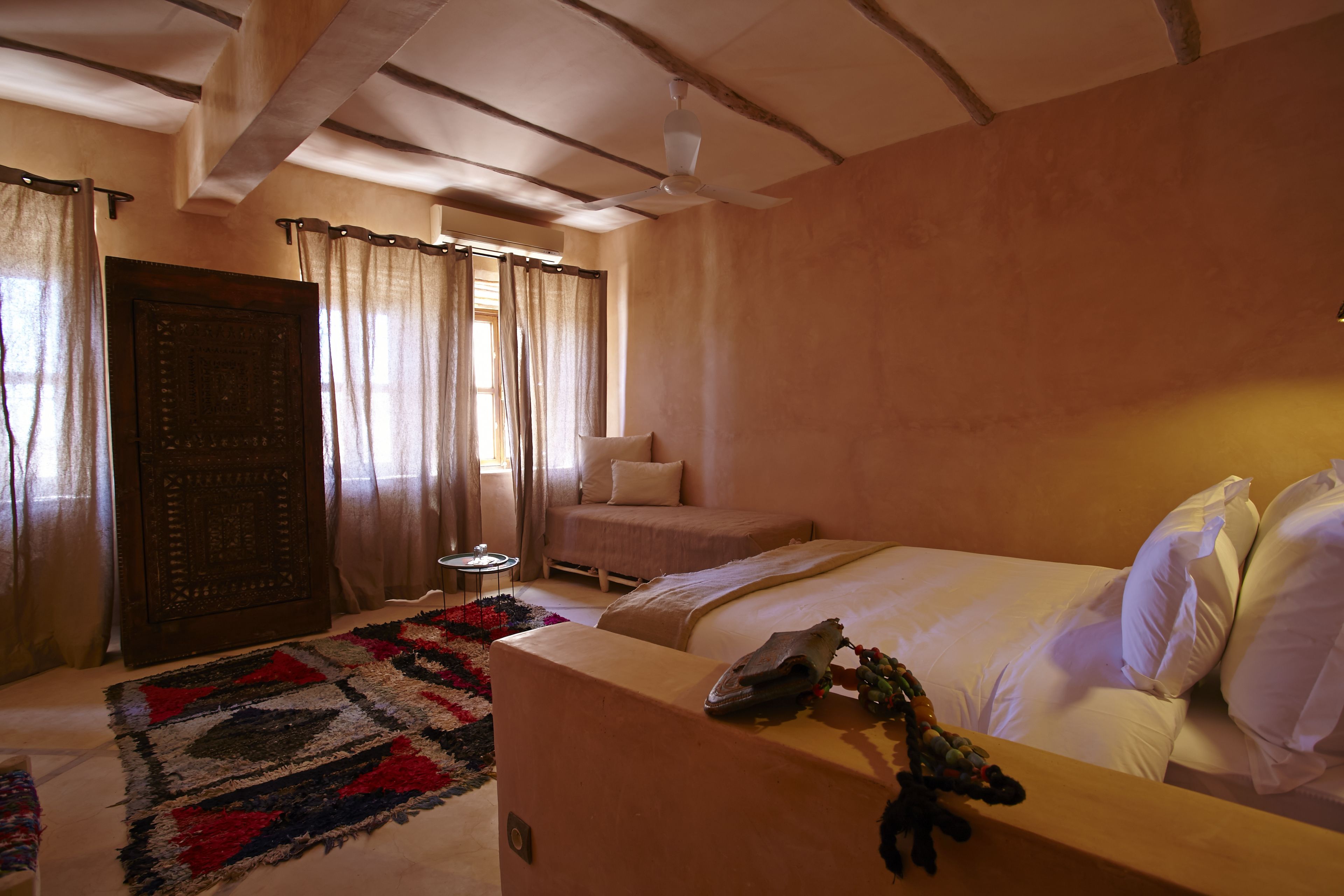 Un dormitorio con cama, sofá, una mesita y ventilador de techo.