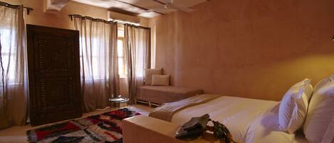 Un dormitorio con cama, sofá, una mesita y ventilador de techo.