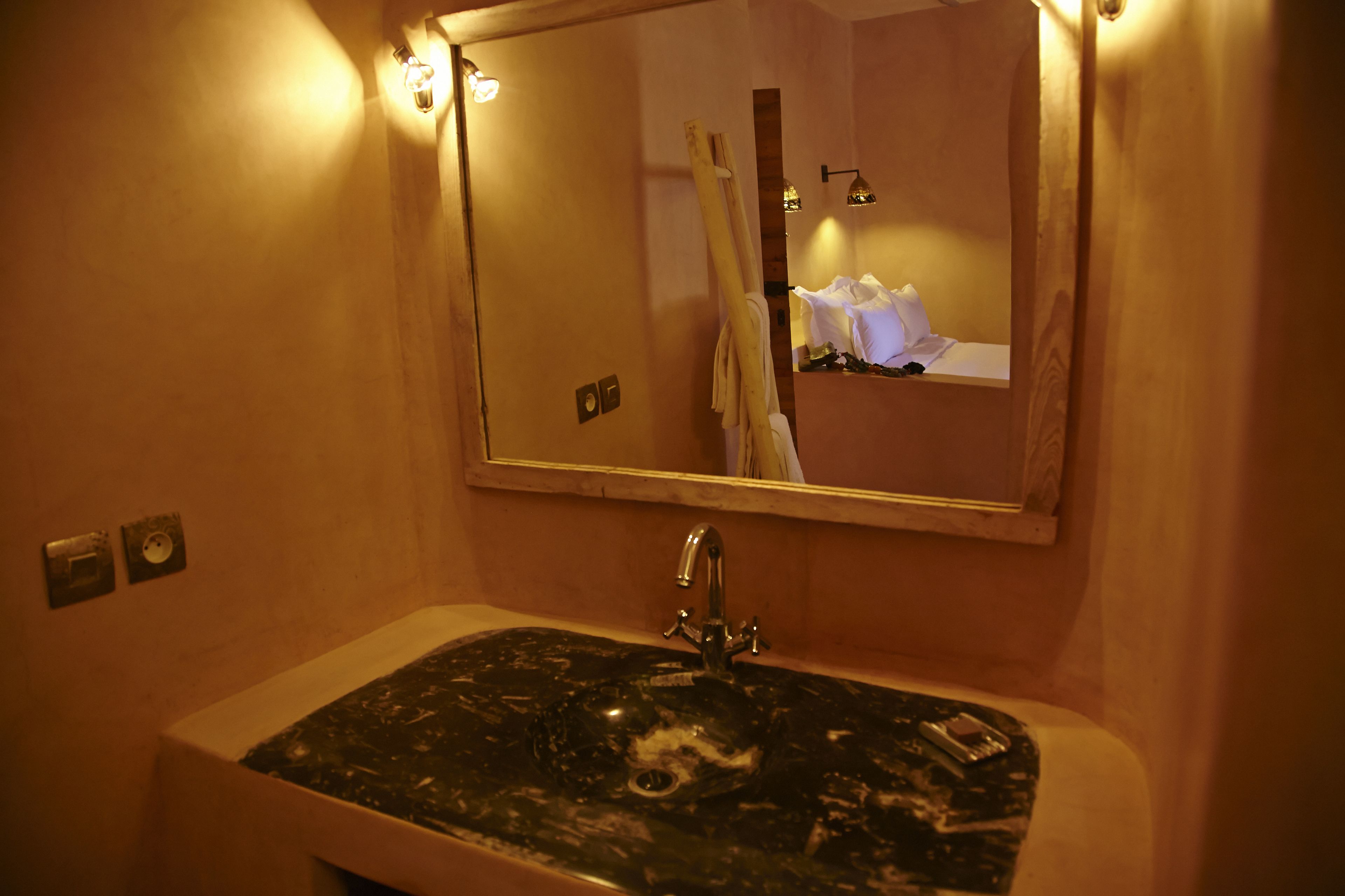 A bathroom with a black marble sink, a mirror, and a towel rack.