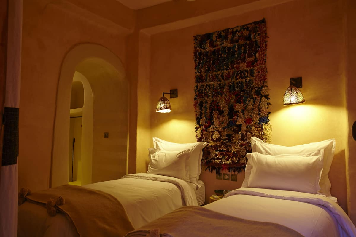 Ein Hotelzimmer mit zwei Betten, einer Wandteppich und Wandleuchten.
