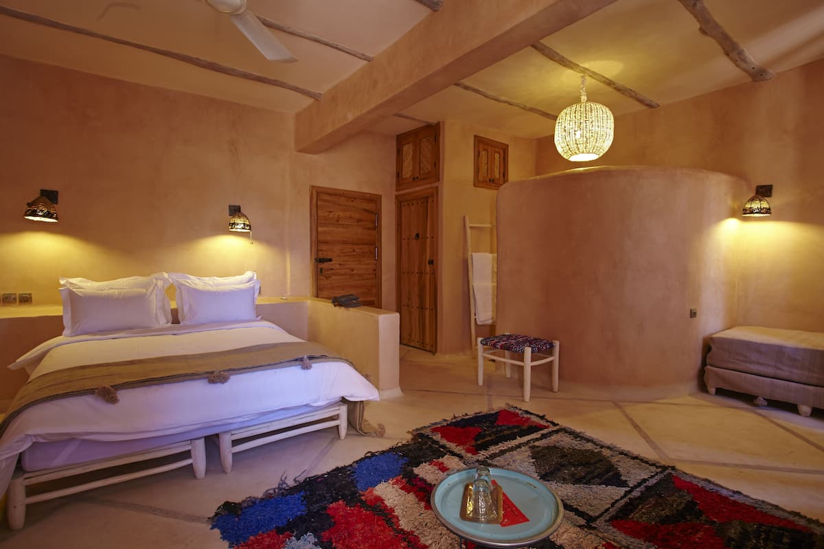 Ein Schlafzimmer mit einem Bett, einem Sessel, einem kleinen Tisch und einer Pendelleuchte.