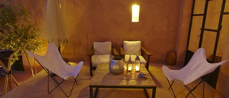 An outdoor seating area with two white chairs, a table, and a lantern.