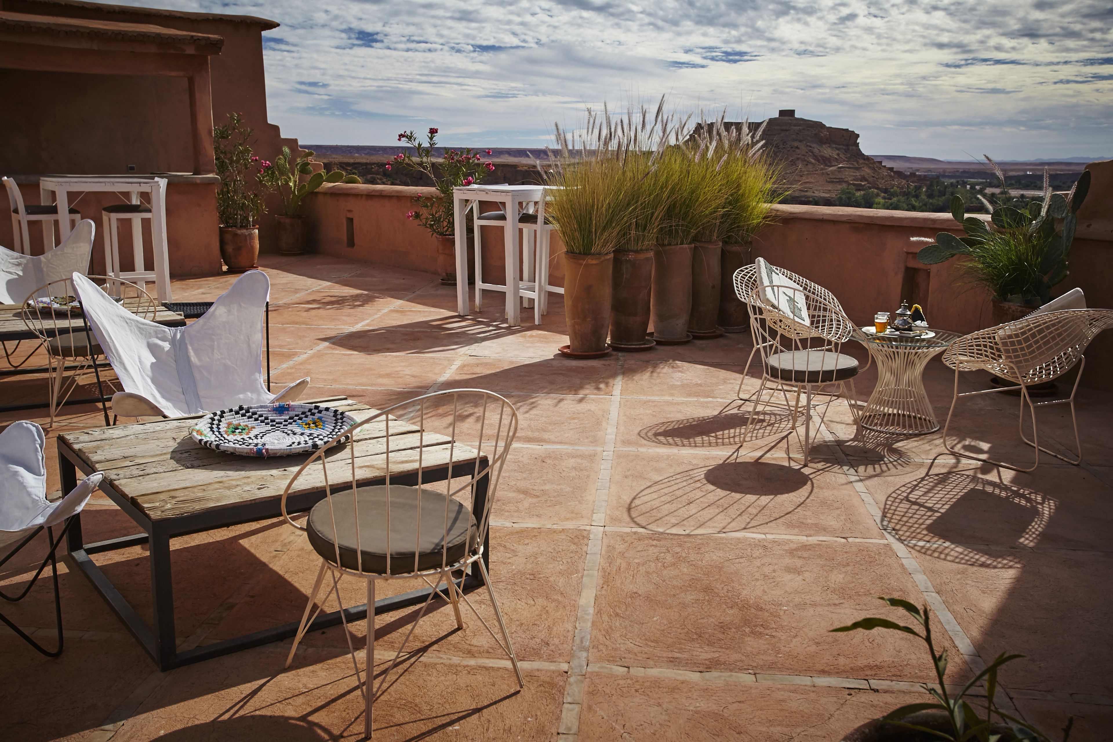 A rooftop terrace with outdoor furniture, potted plants, and a scenic view.