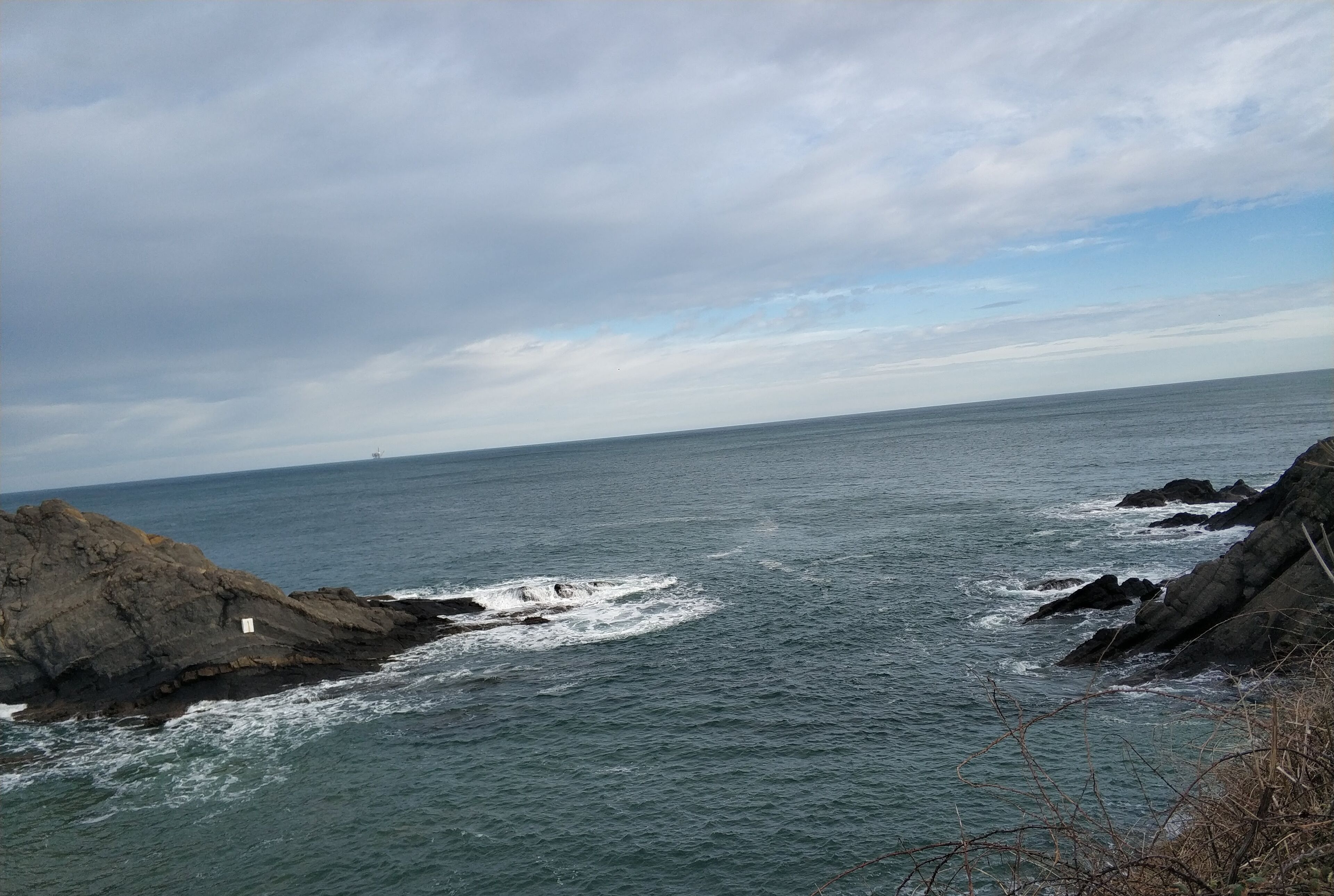 Et kystlandskab med klippeformationer og havet.