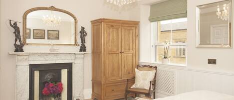 A bedroom with a fireplace, wooden wardrobe, and a large bed.