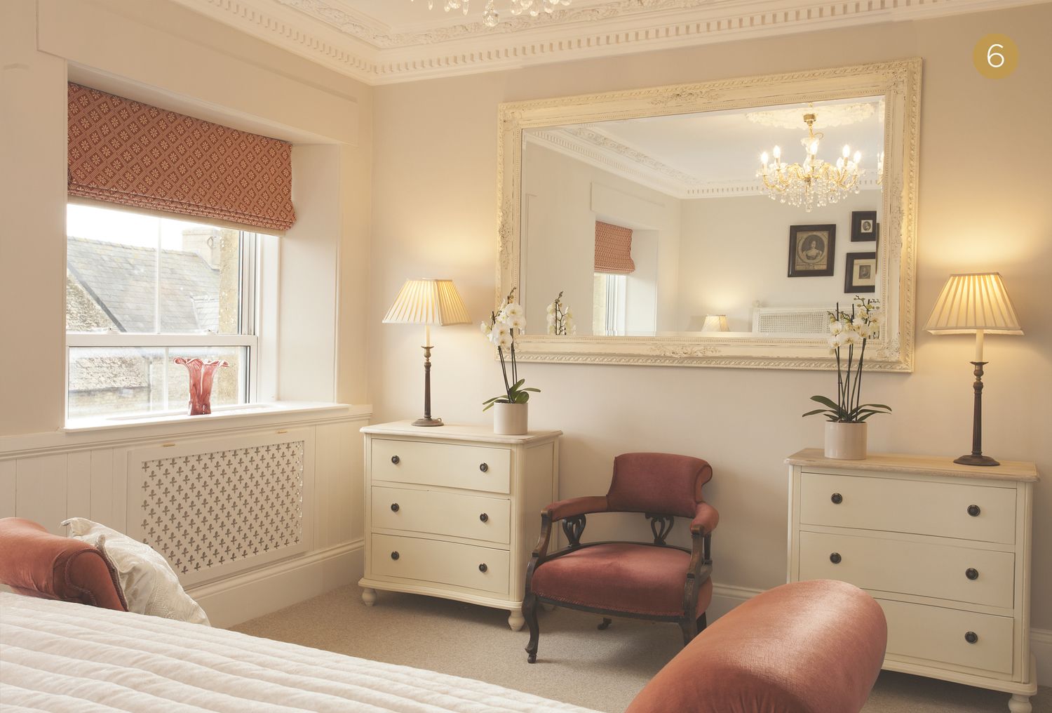 A bedroom with a large mirror, two bedside tables with lamps, a chair, and a bed.
