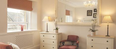 A bedroom with a large mirror, two bedside tables with lamps, a chair, and a bed.
