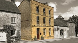 A two-story building with a stone facade and a yellowish-brown color. - Victoria House Stow (Cheltenham)