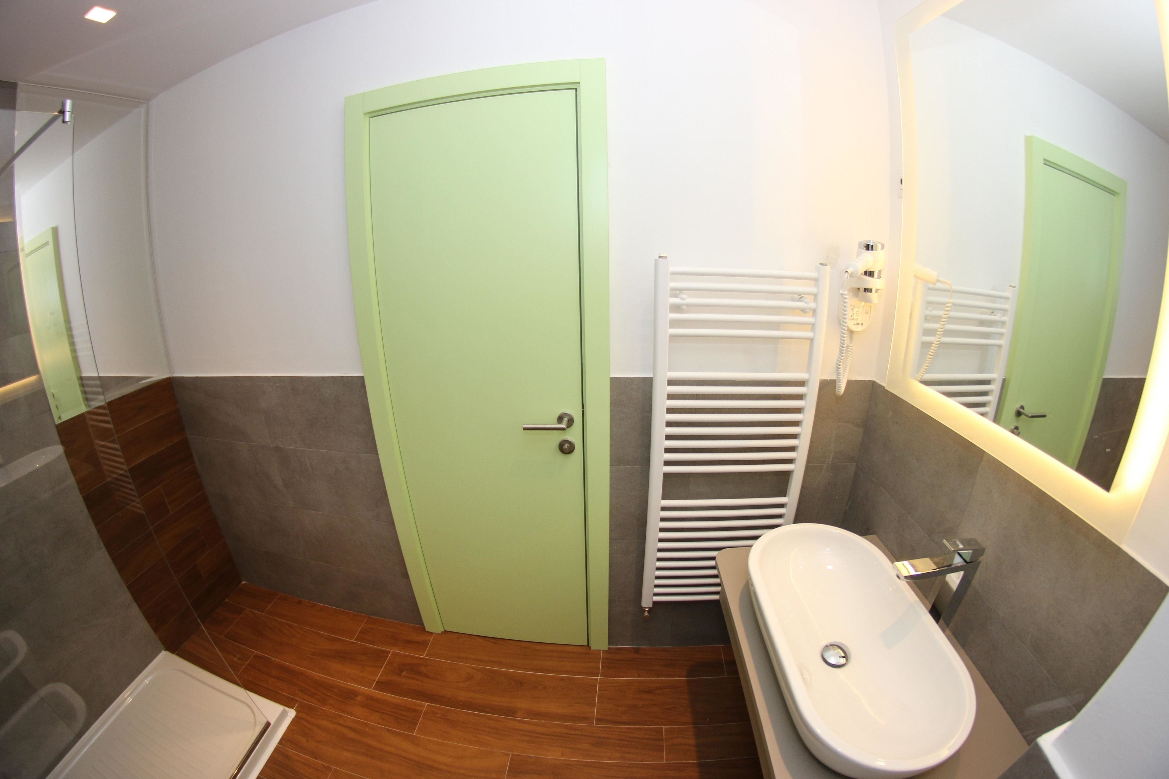 A bathroom with a green door, a white bathtub, a white towel rack, and a shower area.