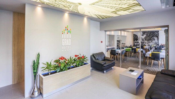 Un espace d’accueil d’hôtel au design moderne, comprenant un comptoir d’accueil, un coin salon et une vue sur la salle à manger.