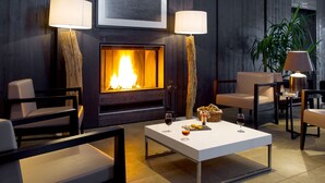 Un área de lounge moderna con chimenea, asientos y una mesa con aperitivos y copas de vino.