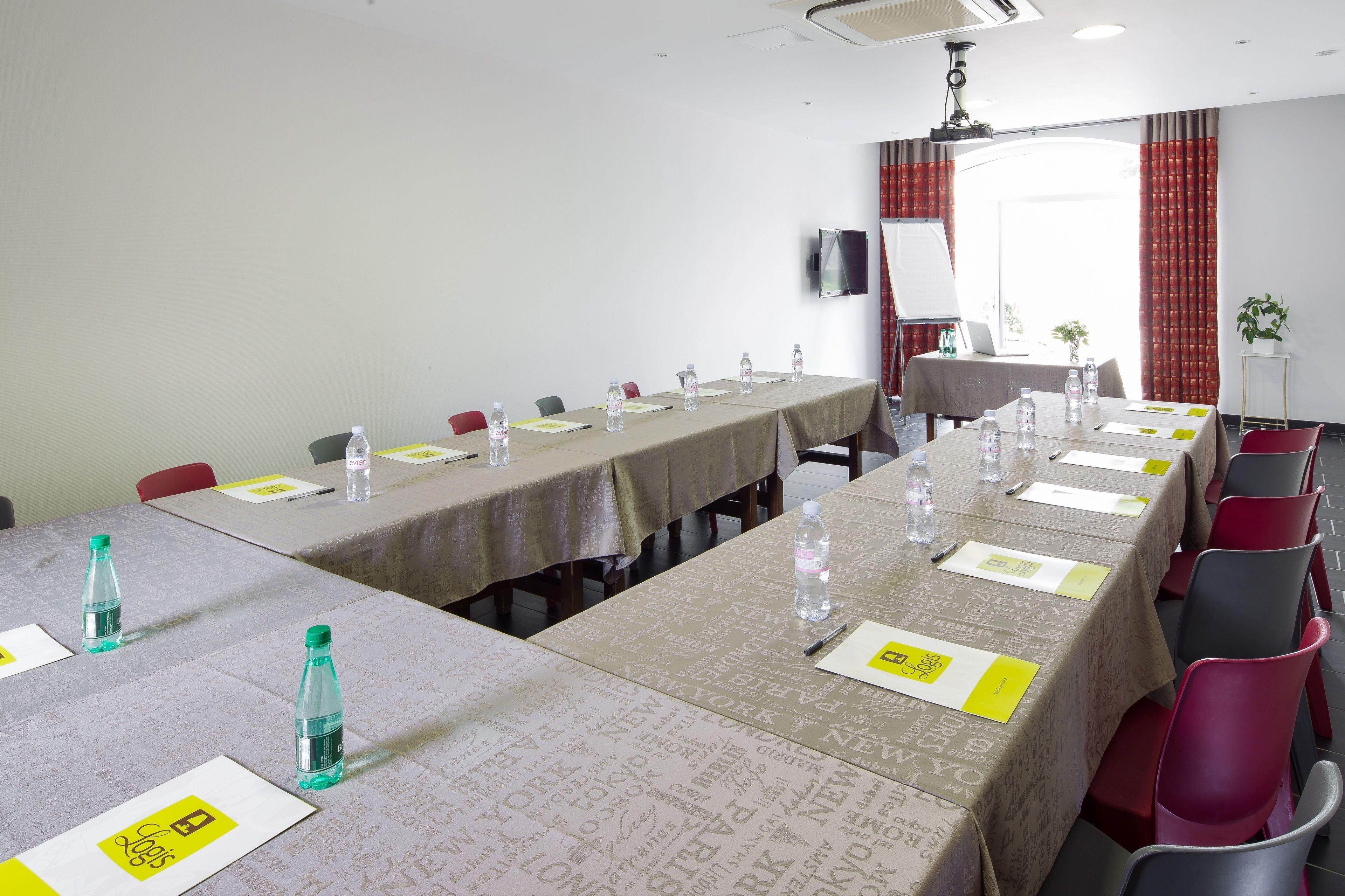 A conference room with long tables, chairs, water bottles, and name tags.
