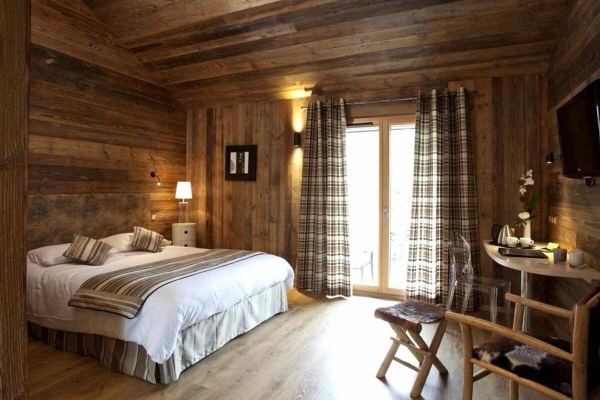 A wooden cabin bedroom with a bed, a desk, and a chair.
