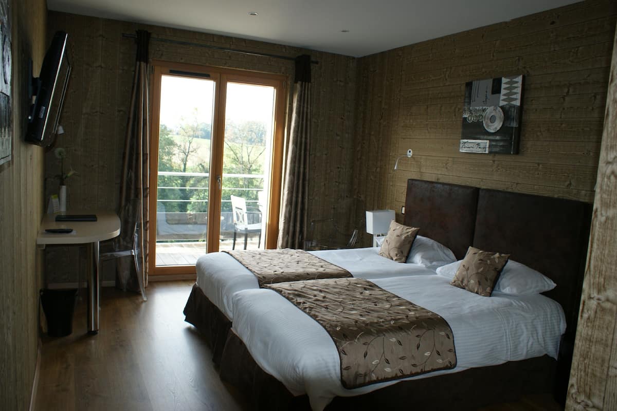 A hotel room with two beds, a desk, and a chair.