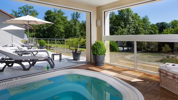 Zona de piscina en la azotea con sillones de descanso, jacuzzi y plantas en macetas.