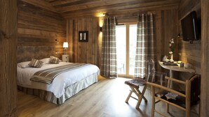 Un dormitorio de cabaña de madera con cama, mesita de noche, lámpara y televisor montado en la pared.