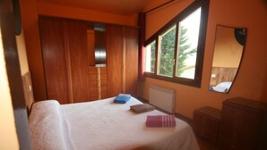 Un dormitorio con cama, ventana, espejo y muebles de madera.