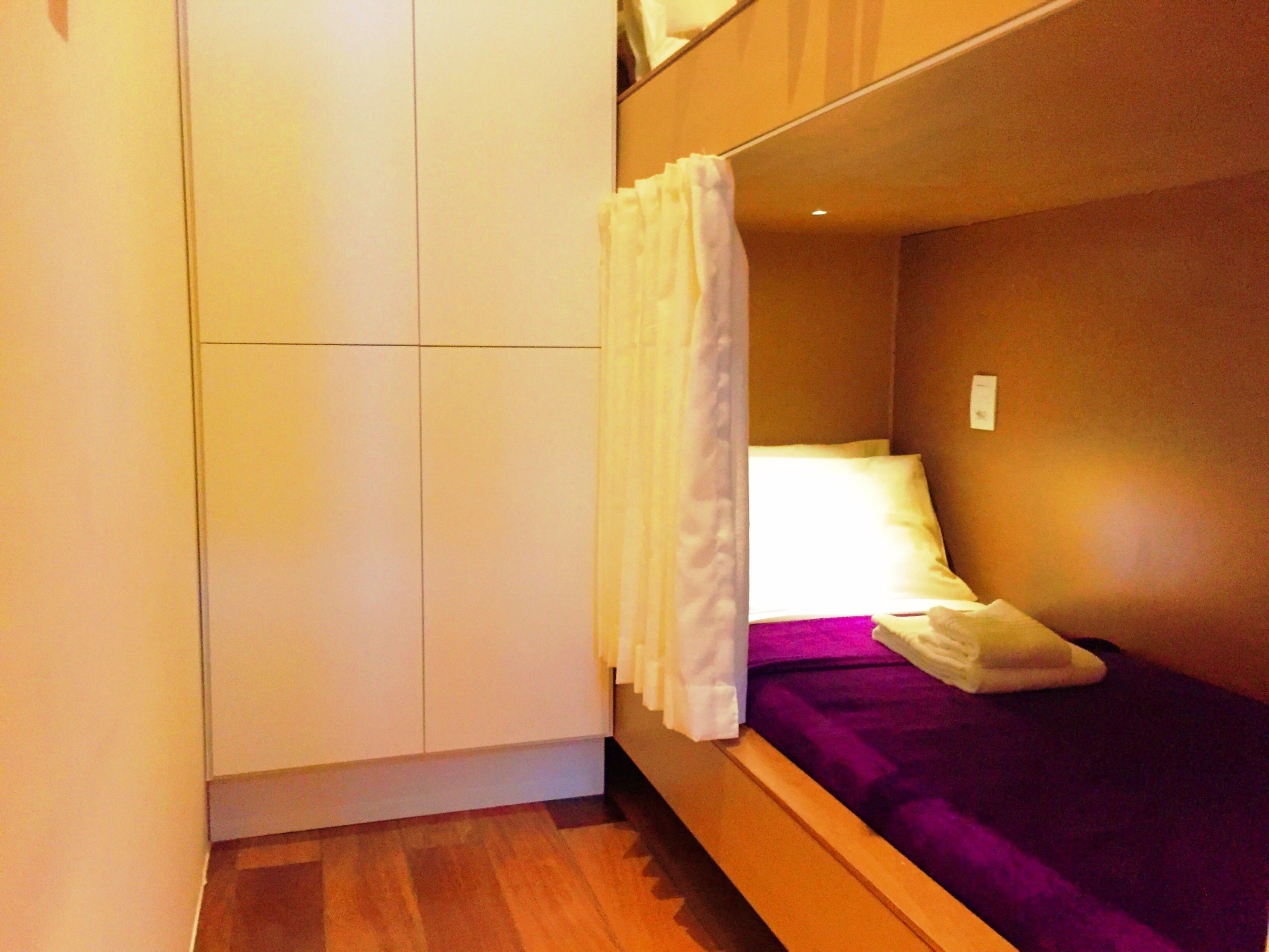 Une petite pièce, de taille modeste, comprenant un lit, une armoire et un rideau.