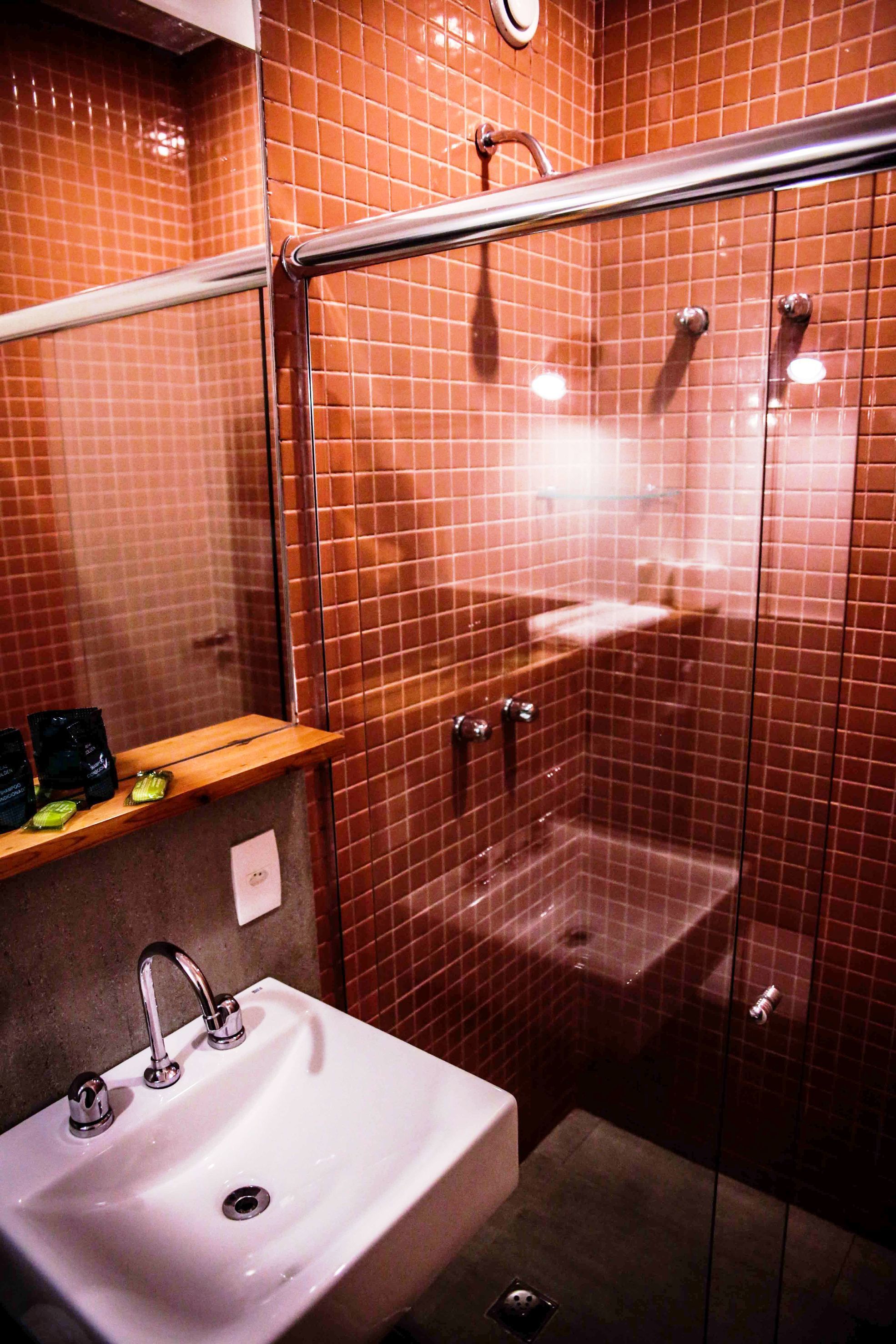A bathroom with a sink, mirror, and shower enclosure.