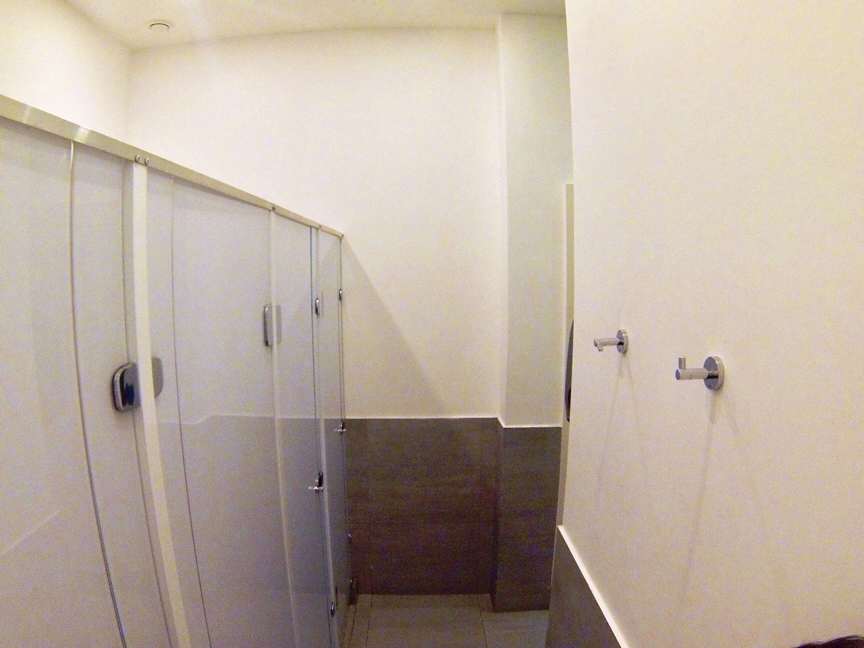 A bathroom with a glass shower enclosure, a white sink, and a towel rack.