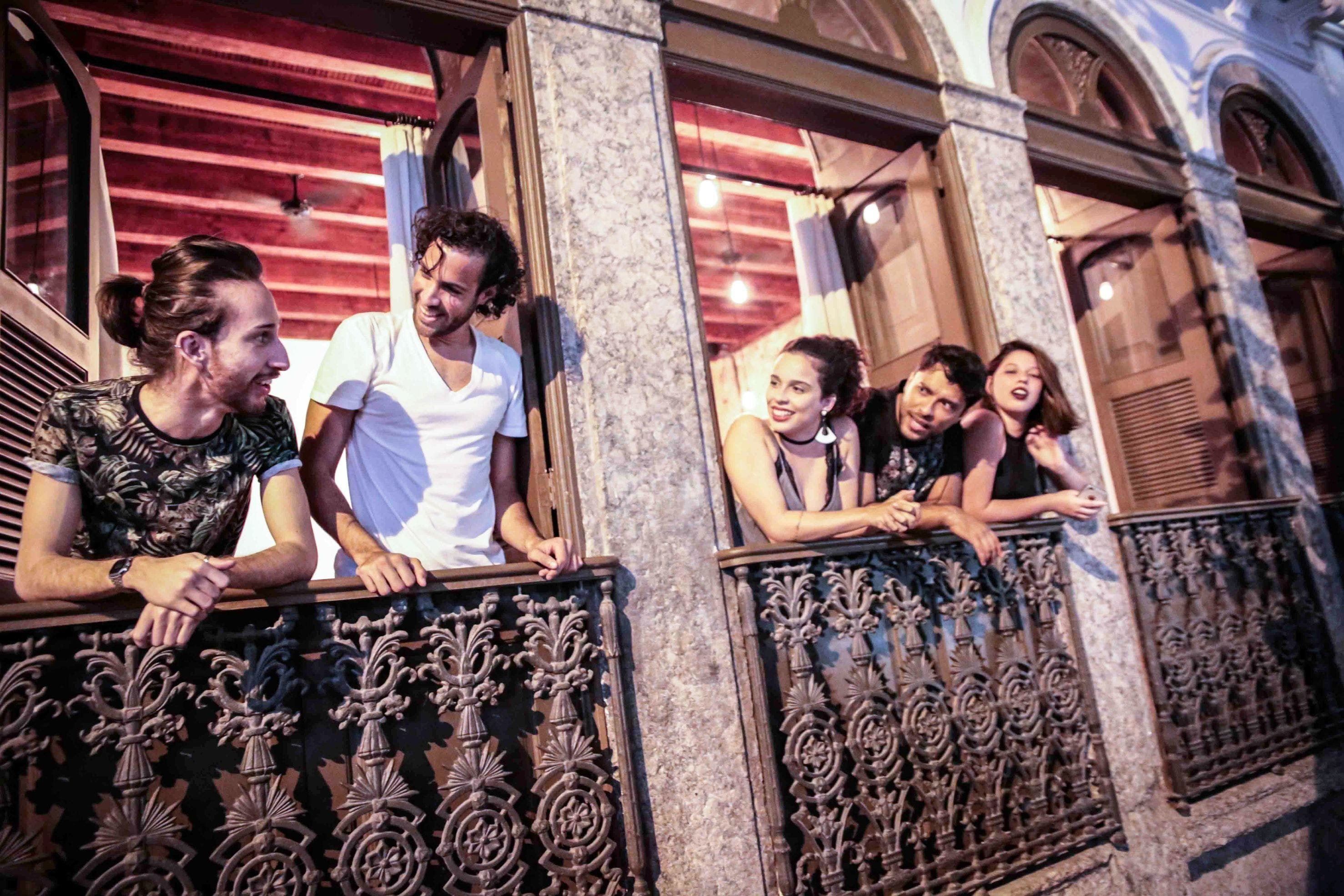 Een groep mensen staat op een balkon met sierlijk ijzerwerk.