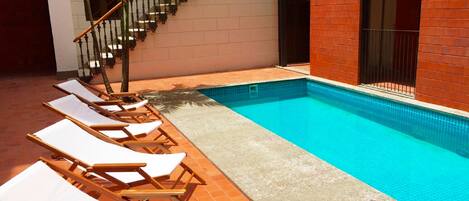 A swimming pool with lounge chairs and a staircase.