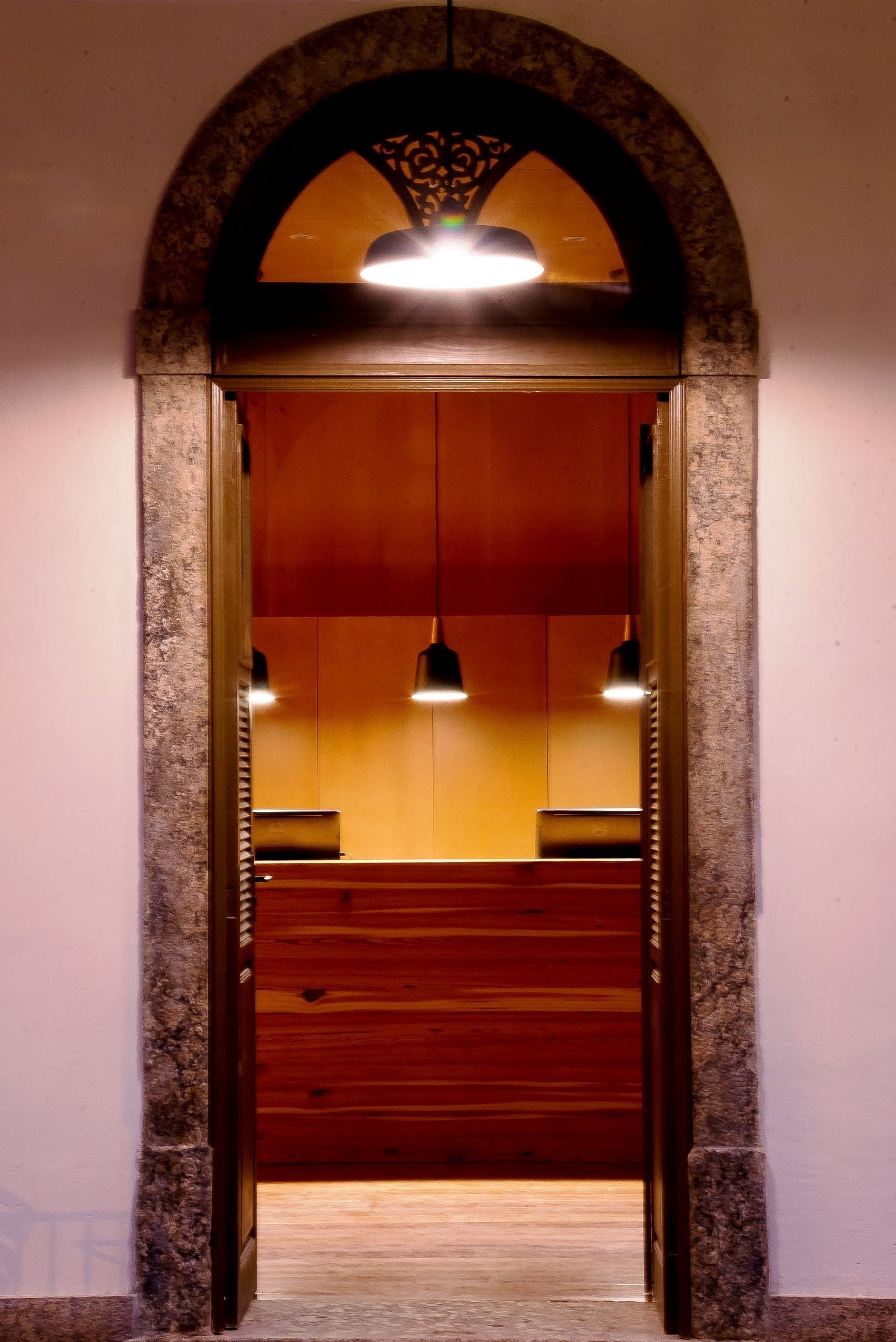 Un arco de entrada que conduce a una habitación con paneles de madera y un banco.