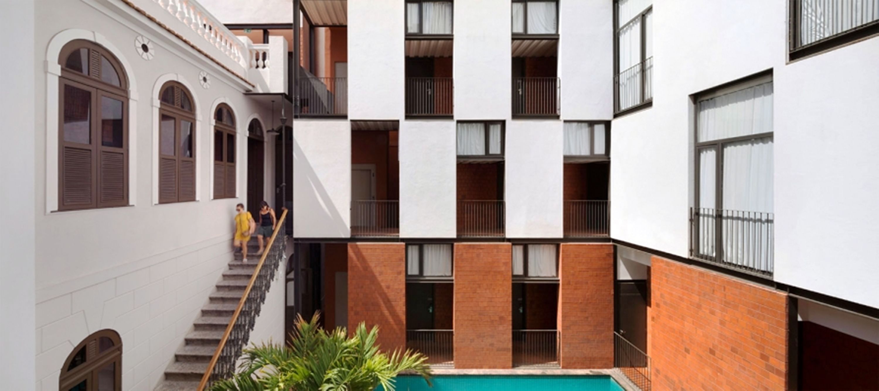 A multi-story building with a central courtyard featuring a swimming pool.