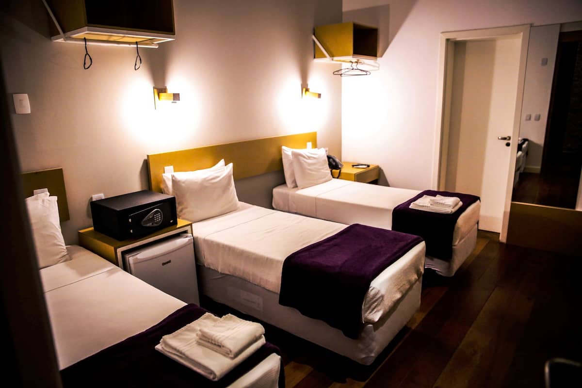 Habitación de hotel con dos camas, un escritorio pequeño, un microondas y una mesita de noche con un teléfono.