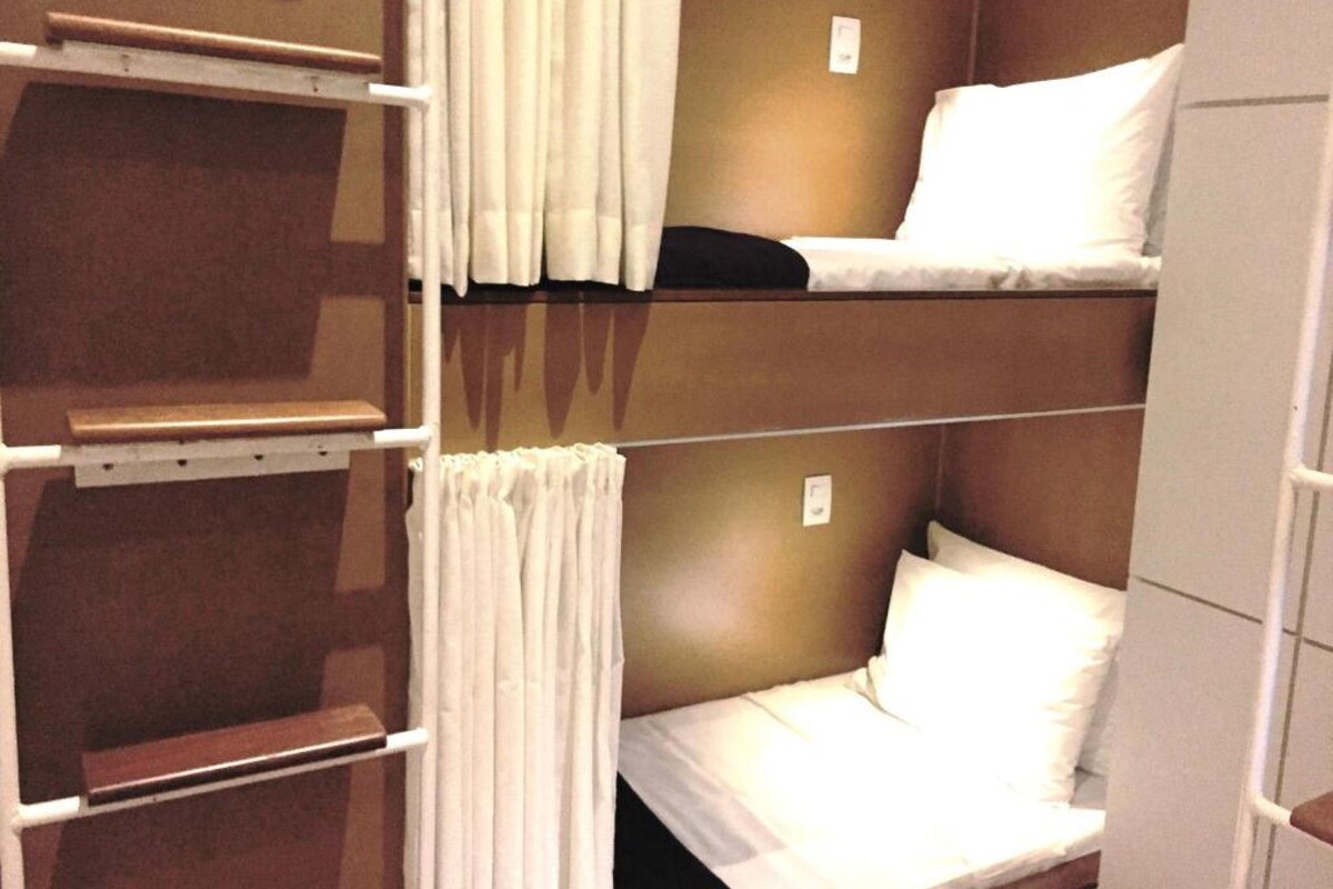 A bunk bed room with a ladder and curtains.