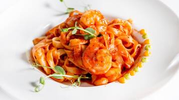 A plate of pasta with shrimp and corn, garnished with microgreens.