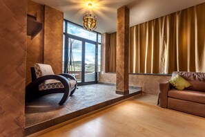 A modern living room with a sofa, a chair, a large window, and a view of the outdoors. - Business Hotel Conference Center & Spa (Targu Mures)