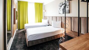 Ein Hotelzimmer mit zwei Betten, einem Holztisch, einem Spiegel und einem Bild an der Wand.