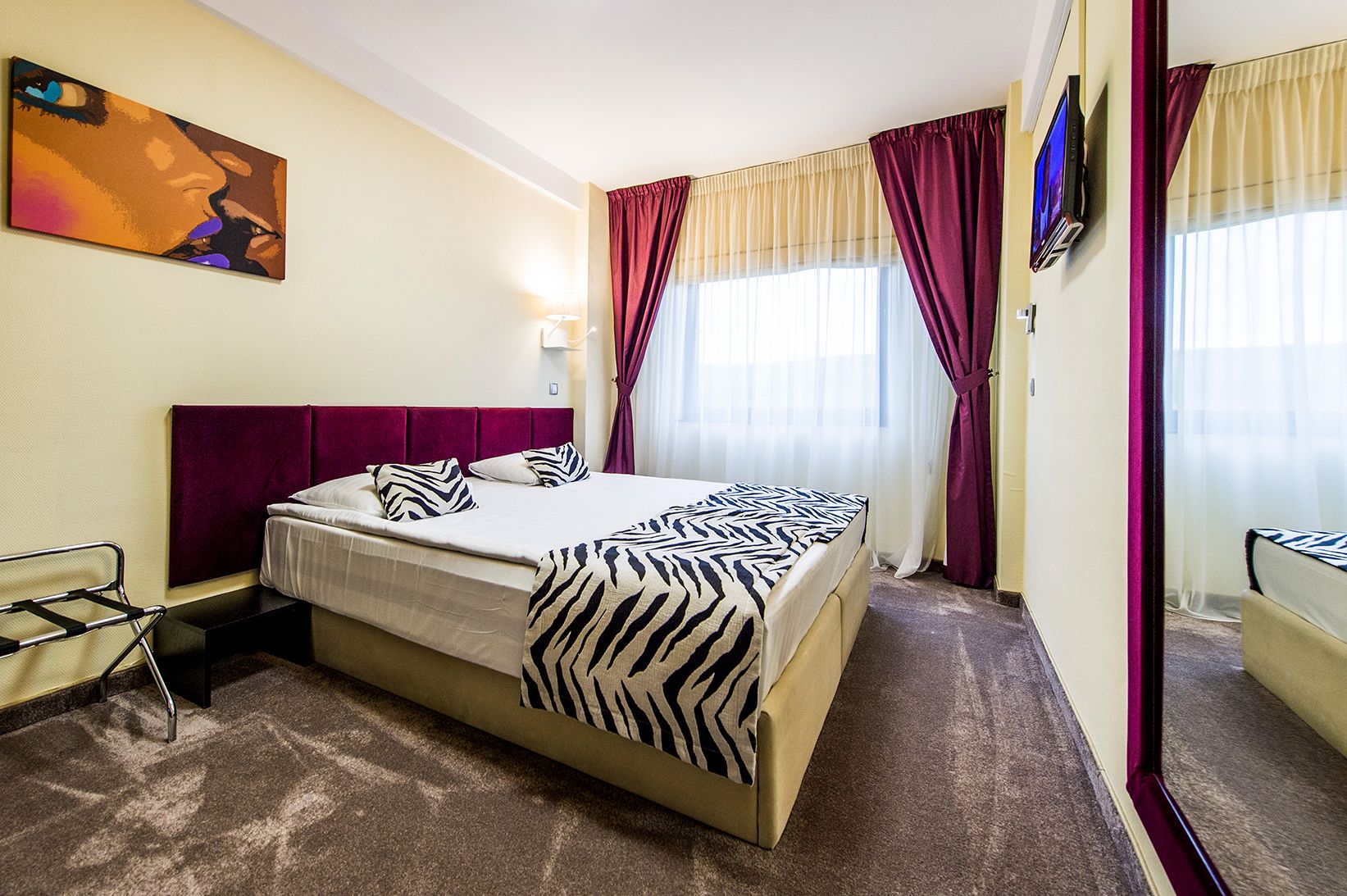 Een hotelkamer met een bed, een televisie en een schilderij aan de muur.
