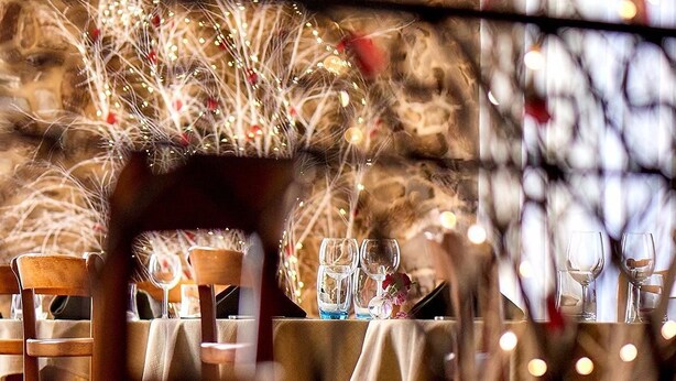En restaurant med borde dækket til spisning, stole og en hyggelig atmosfære med lyskæder.
