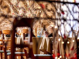 Un restaurante con mesas dispuestas para comer, sillas y un ambiente cálido con luces colgantes.