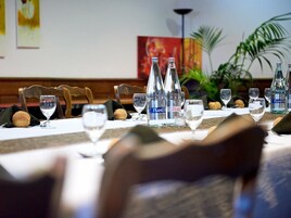 Una mesa de comedor dispuesta con copas de vino, botellas de agua y panecillos.