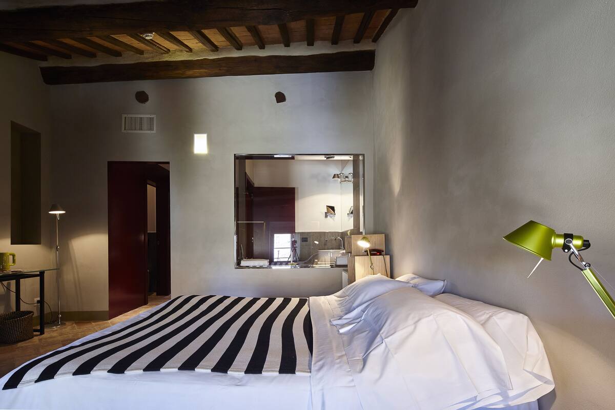Un dormitorio con una cama, un escritorio, una lámpara y un espejo.