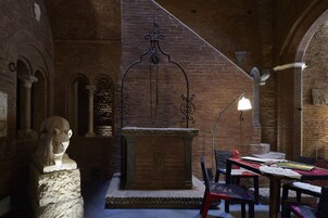 Una stanza con camino, colonne in pietra e una scultura a busto.